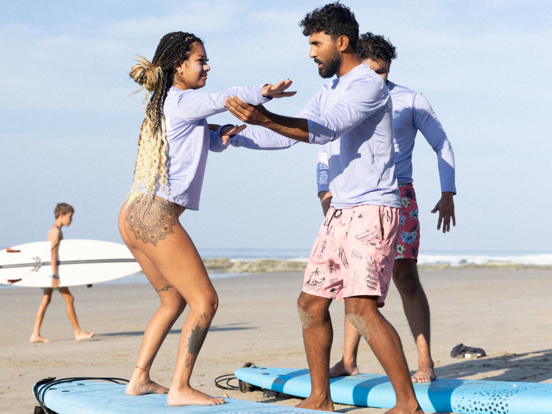 Coach guiding a surfer into her pop-up stance on the sand