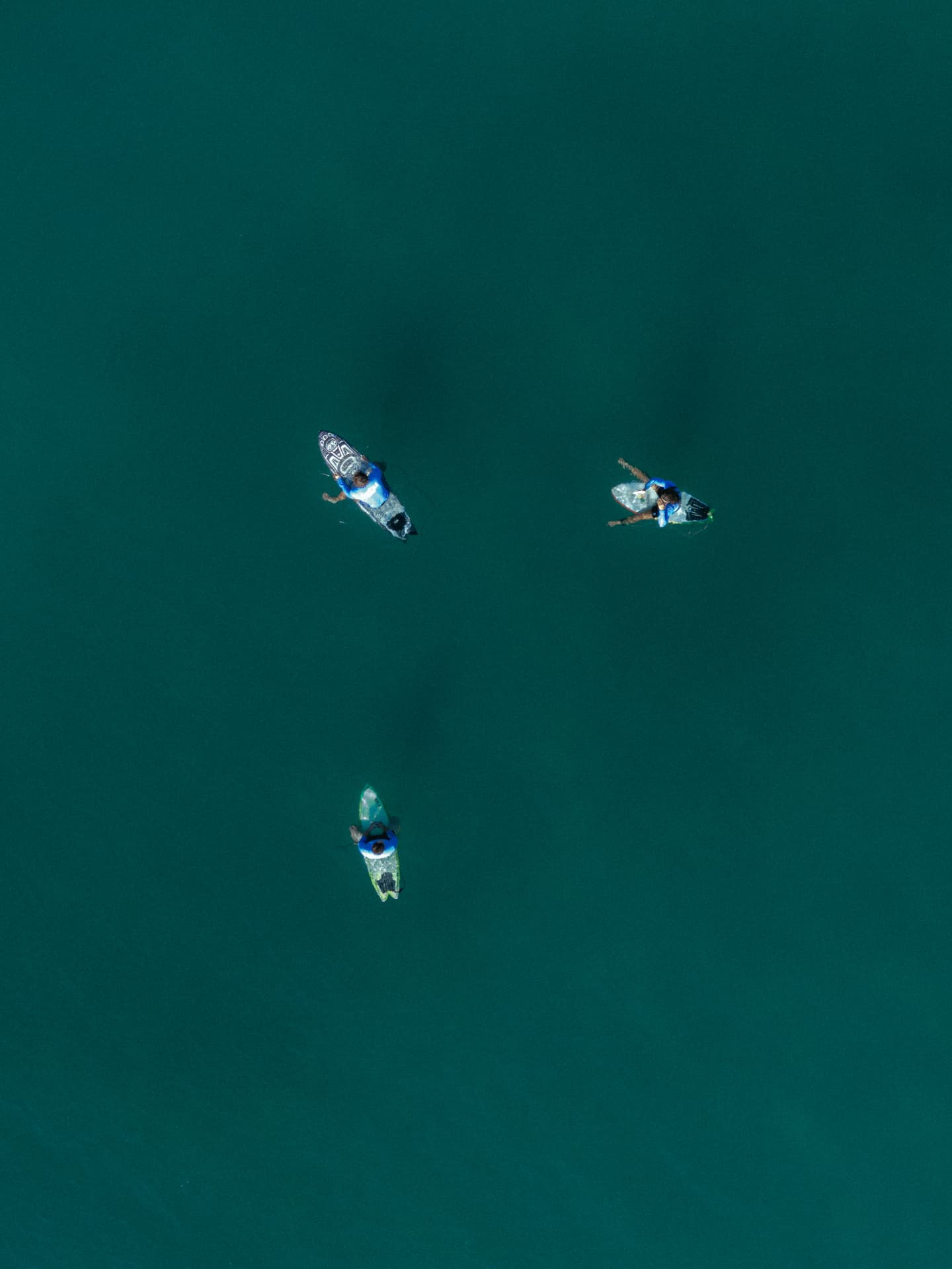 Surfers floating over deep green water