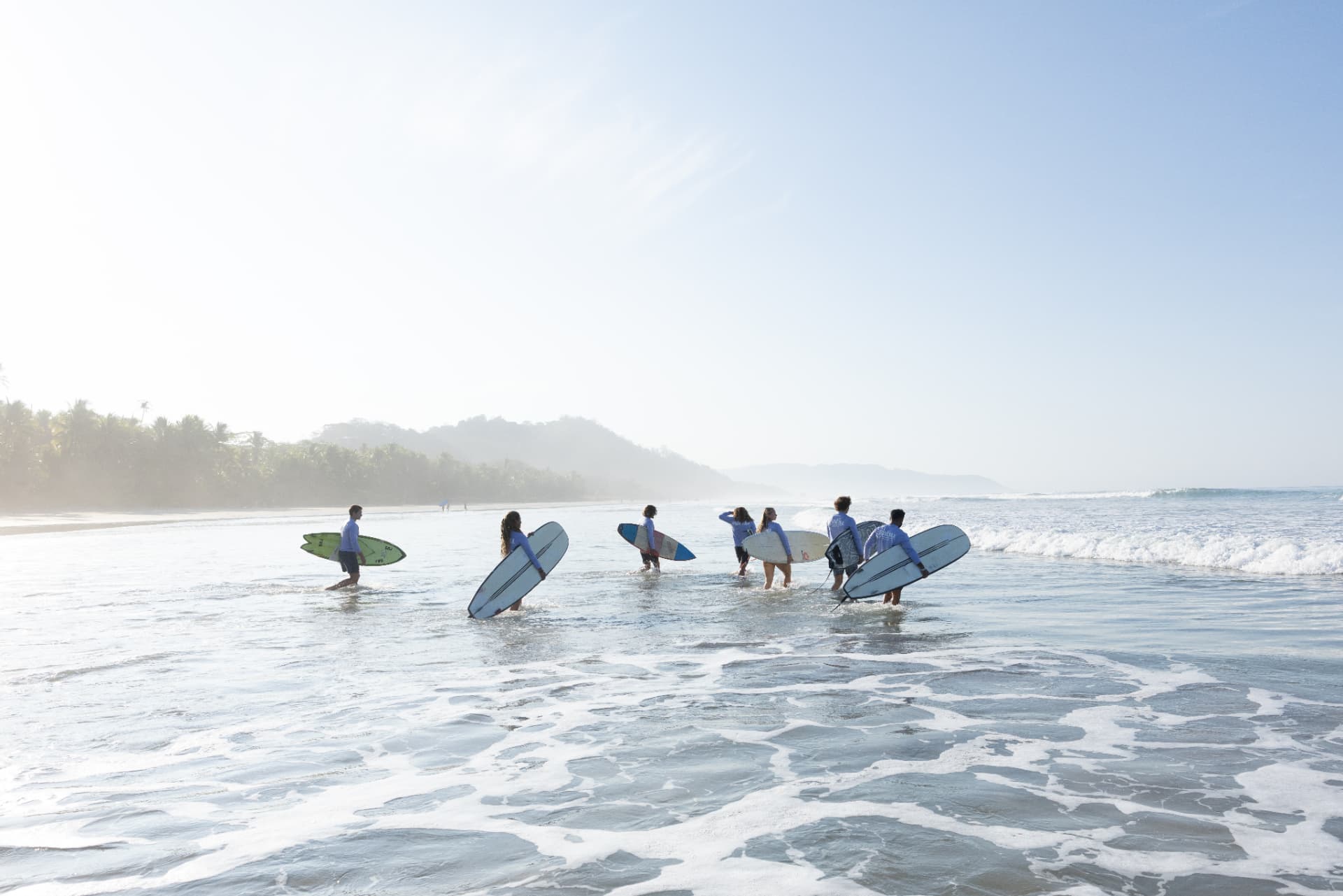 Kahu surfers carrying their boards into the surf together at Santa Teresa